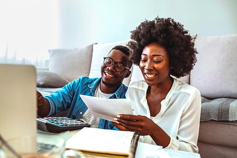 Smiling woman taking notes in front of laptop